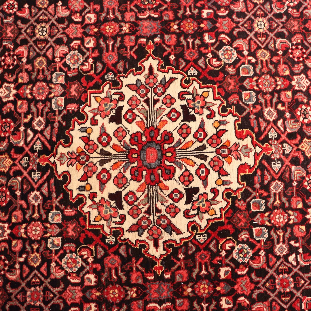 Vintage Persian rug with a faded, aged appearance, showcasing muted colors and intricate patterns. The rug is spread out on a wooden floor, with sunlight streaming in from a nearby window. This image accompanies an article discussing the unique charm and enduring appeal of vintage Persian rugs, which are at least 50 years old and evoke a sense of nostalgia and timeless elegance.