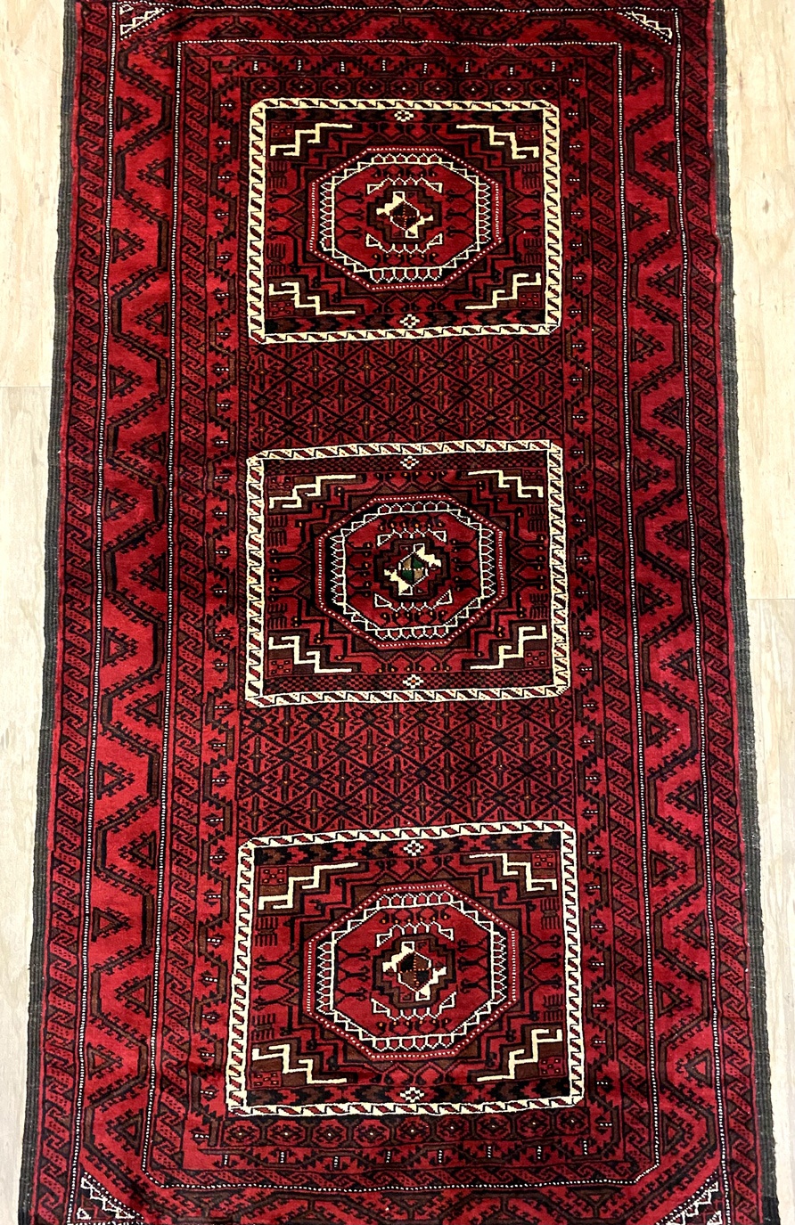 A Balouchi rug with intricate designs and beautiful colors, woven by Balouchi tribes in eastern Iran. The rug is a smaller size, making it a great choice for smaller rooms or areas.