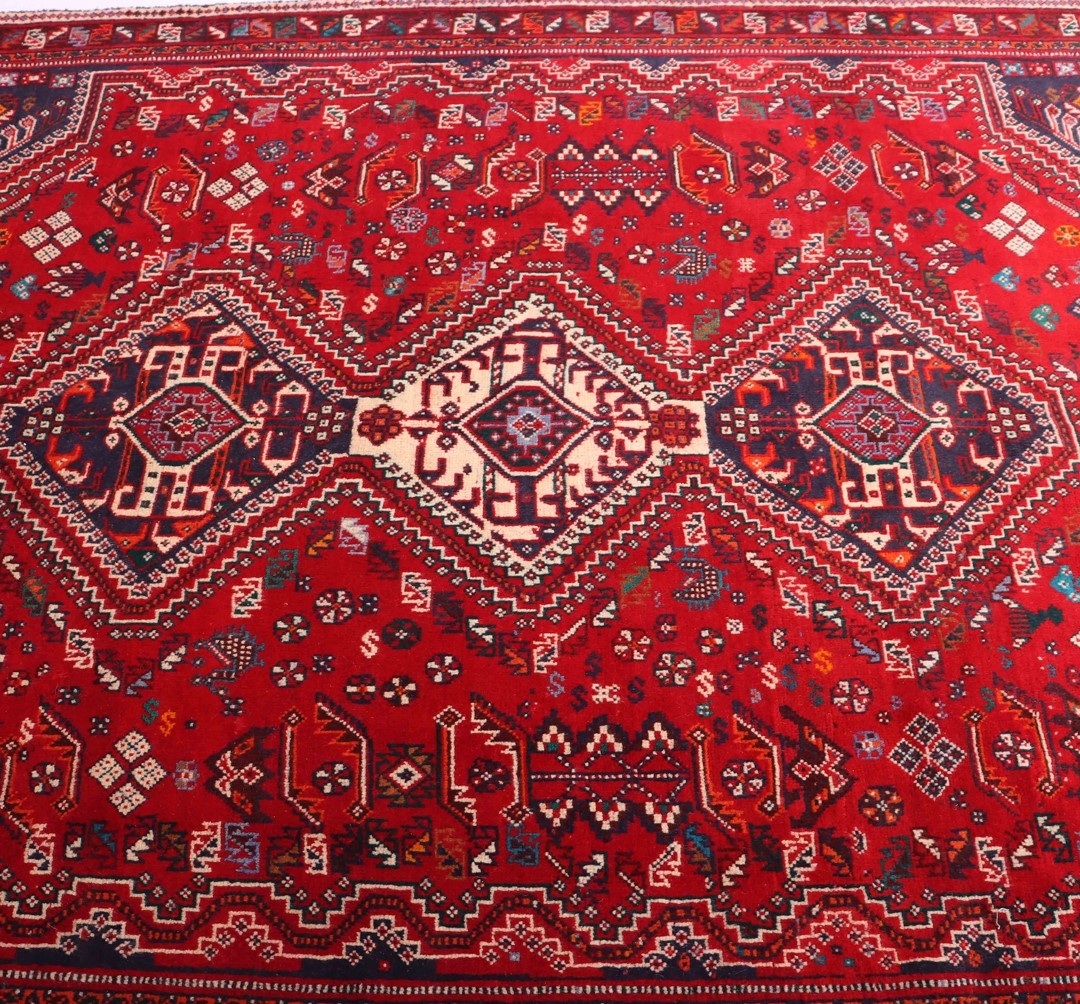 7 Compelling Reasons to Adorn Your Home with a Persian Rug 6 Close-up of a bold and colorful Shiraz rug, featuring intricate geometric designs in shades of red, blue, and cream.