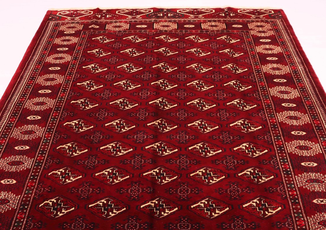 Nomadic Persian rug showcasing a bold, geometric pattern in a variety of bright colors. The rug is shown on a hardwood floor, with natural light streaming in from a nearby window. This image accompanies an article discussing the unique characteristics of nomadic Persian rugs, which are often handwoven by nomadic tribes in Iran and feature designs that reflect the tribe's culture and traditions. Nomadic Persian rugs can add a vibrant and culturally rich touch to any space.